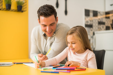 Little girl and her father enjoy drawing together at their home.の写真素材
