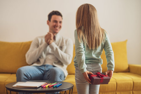 Happy daughter holding gift for her father.の写真素材