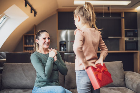 Happy mother is getting gift from her daughter.の写真素材