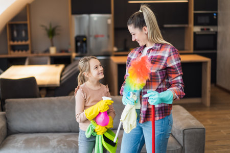 Happy mother and daughter cleaning house together.の写真素材