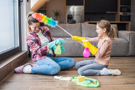 Happy mother and daughter having fun while cleaning  house together.