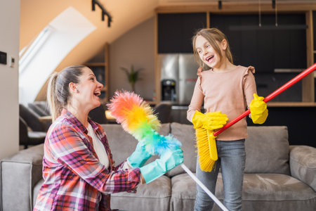 Happy mother and daughter having fun while cleaning  house together.の写真素材