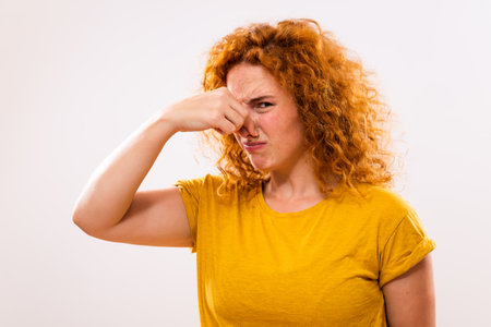 Shocked ginger woman doesn't like how something smells.の写真素材