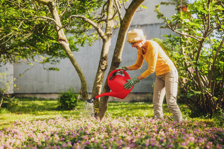 Happy senior woman enjoys watering plants in her garden.の写真素材