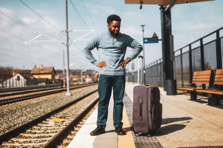 Angry man with a suitcase standing on a railway station.の写真素材