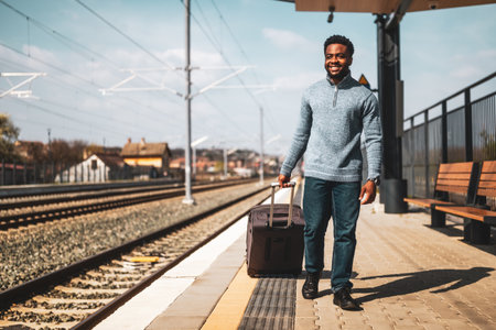 Happy man with suitcase walking on railway station.の写真素材