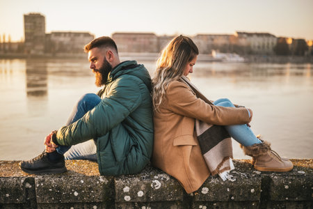 Couple having conflict, man and woman are very angry on each other while sitting outdoor by the river.の写真素材