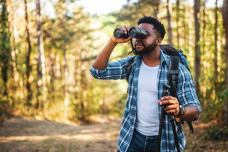 Young man enjoys using binoculars and hiking in nature.の写真素材