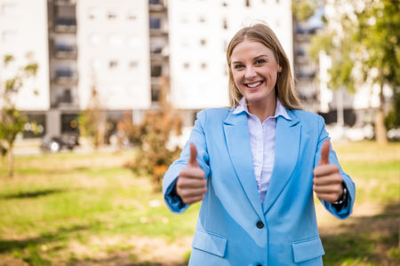 Portrait of successful businesswoman outdoor showing thumbs up.の写真素材