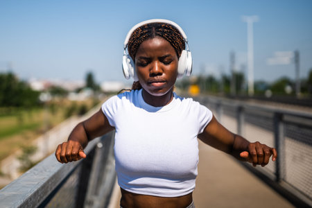 Portrait of sporty confident African-American woman in sportswear exercising and stretching while...