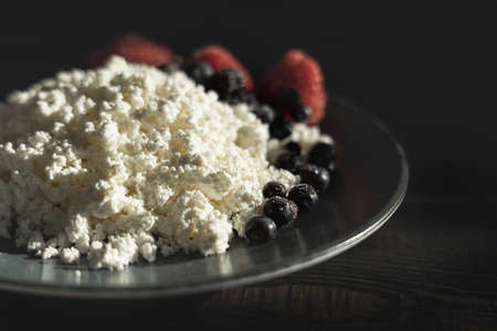 Cottage cheese with berries on a dark plate.の写真素材