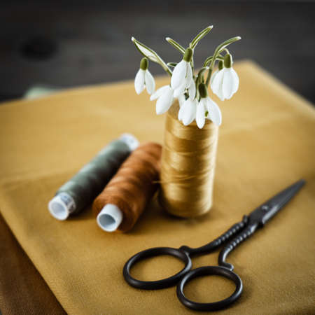 Yellow linen fabric and sewing threads on the seamstress's work desk.の写真素材