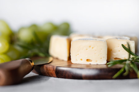 Camamber cheese on a wooden board. Against the background of grapes.