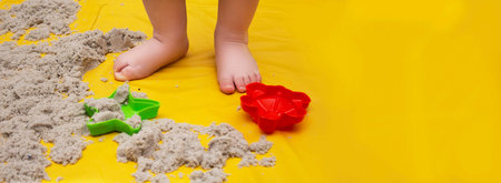 child's feet on an oilcloth for games with kinetic sand, a template with a place for text, the...