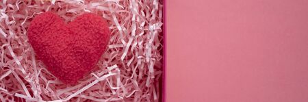 A plush pink heart lies in a gift box. template with space for textの写真素材