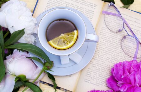 Summer layout with tea, book and peonies, on a wooden background. Summer Breakfast. Rustic style.の写真素材