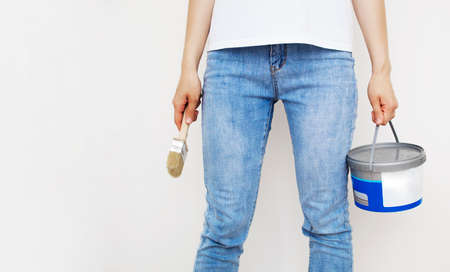 A can of paint and a brush in the hands of a girl, the concept of repair, creativity.の写真素材