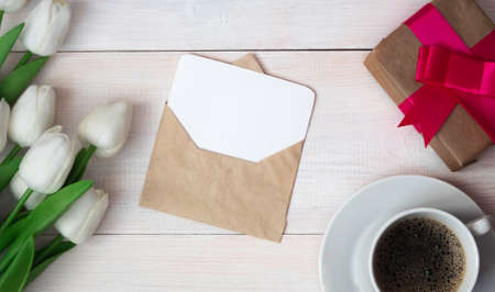 A coffee mug with a bouquet of tulips and a gift box and a clean paper card in an envelope. Happy Mothers Day, Womens Day.の写真素材