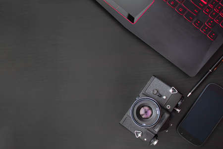 Black smartphone, keyboard, camera on a black background. Business matters. Discreet photography. Free space for text.の写真素材