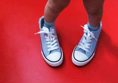 A small child in the sneakers of a large adult. the concept of growing up, the continuity of generations, parental care.の写真素材