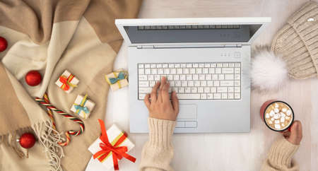 The girls hands on the laptop keyboard. Christmas layout, with laptop and gifts and decorations.の写真素材