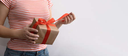 A woman in a white sweater untied the ribbon on the gift. layout with copy space and text spaceの写真素材