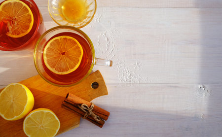 Tea with lemon, cinnamon and honey, on a light wooden background. Layout with space for text.
