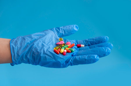 multicolored tablets lie on the doctors hand, the hand is in a medical glove. layout with copy spaceの写真素材