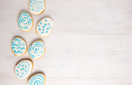 gingerbread in sugar glaze in the shape of Easter eggs on a white wooden background