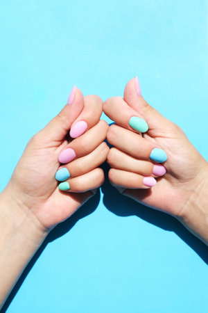womens hands on a blue background show a bright manicure. multicolored nails, copy spaceの写真素材