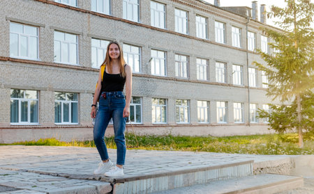 smart female college students on campus outdoors, a girl with a backpack on the background of the school building.の写真素材