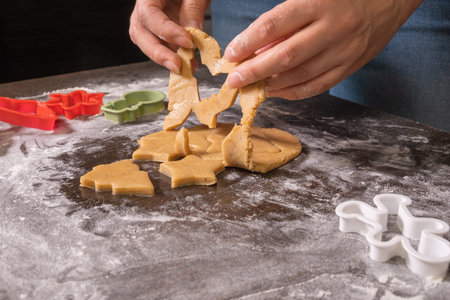 Close-up of female hands cutting out ginger cookies from dough. A woman bakes Christmas cookies....
