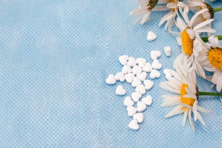 Chamomile and pills in the shape of a heart. Medicines made from natural ingredients.の写真素材