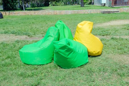 Multicolored beanbag chair in the park on a meadow of green grass.の写真素材