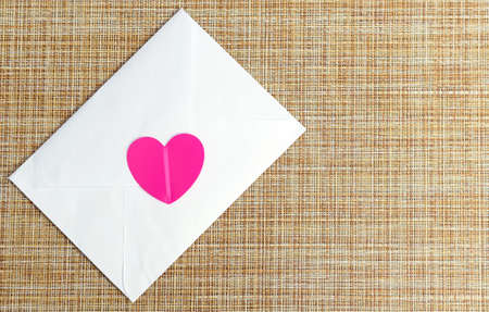 A white envelope with a pink heart. Love letter. Invitation to the wedding. An envelope with a love confession.の写真素材