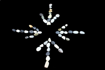 on a black background with small sea bright stones laid in the direction of the arrow in the center