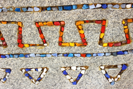 on a gray granite stone with colored stones laid ethnic patternの写真素材