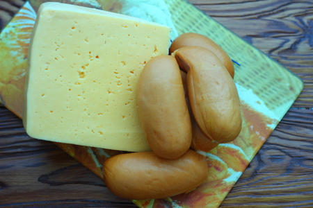 on the board are a small piece of cheese and sausageの写真素材