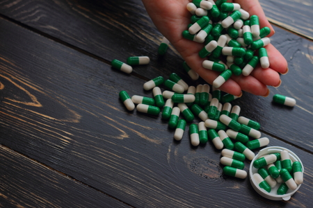 a large number of capsules in his hand on a wooden boardの写真素材