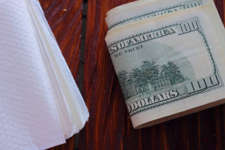 on a wooden board stack of dollars and paper napkins