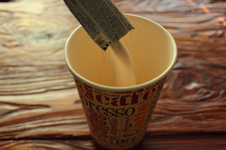 sugar is poured into a glass from a bagの写真素材