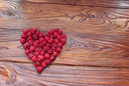 on a wooden board lined heart of raspberriesの写真素材