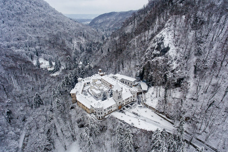Aerial drone photo of a beautiful monastery in Romania set in a charming winter landscape with snowの写真素材