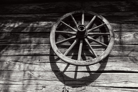 Old wooden wheel on the wall of an antique wooden barn, black and white photoの写真素材