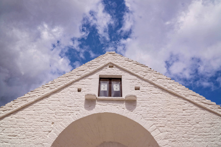Architecture detail of a white wall and small window on a cloudy sky backgroundの写真素材