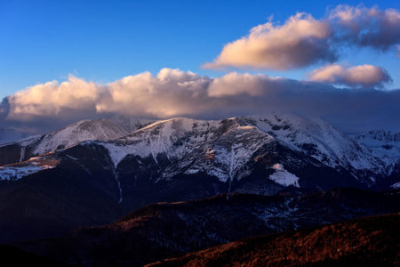 Mountain winter scenery in the high Carpathian mountains of Romania with snow, clouds in the sunset