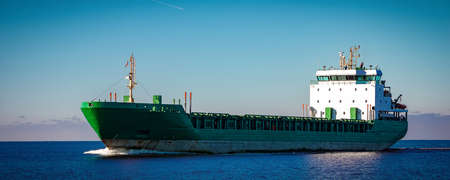 Green cargo ship moving in still water of Baltic seaの写真素材