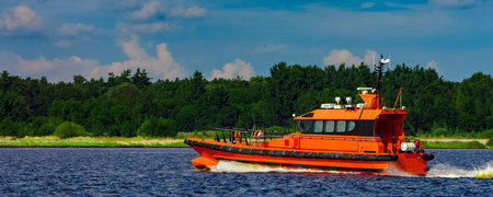 Orange pilot boat moving by the river in Europe. Rescue serviceの写真素材