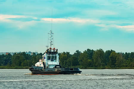 Black tug ship moving to the cargo terminal. Industrial serviceの写真素材
