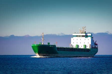 Green cargo ship moving in still water of Baltic seaの写真素材